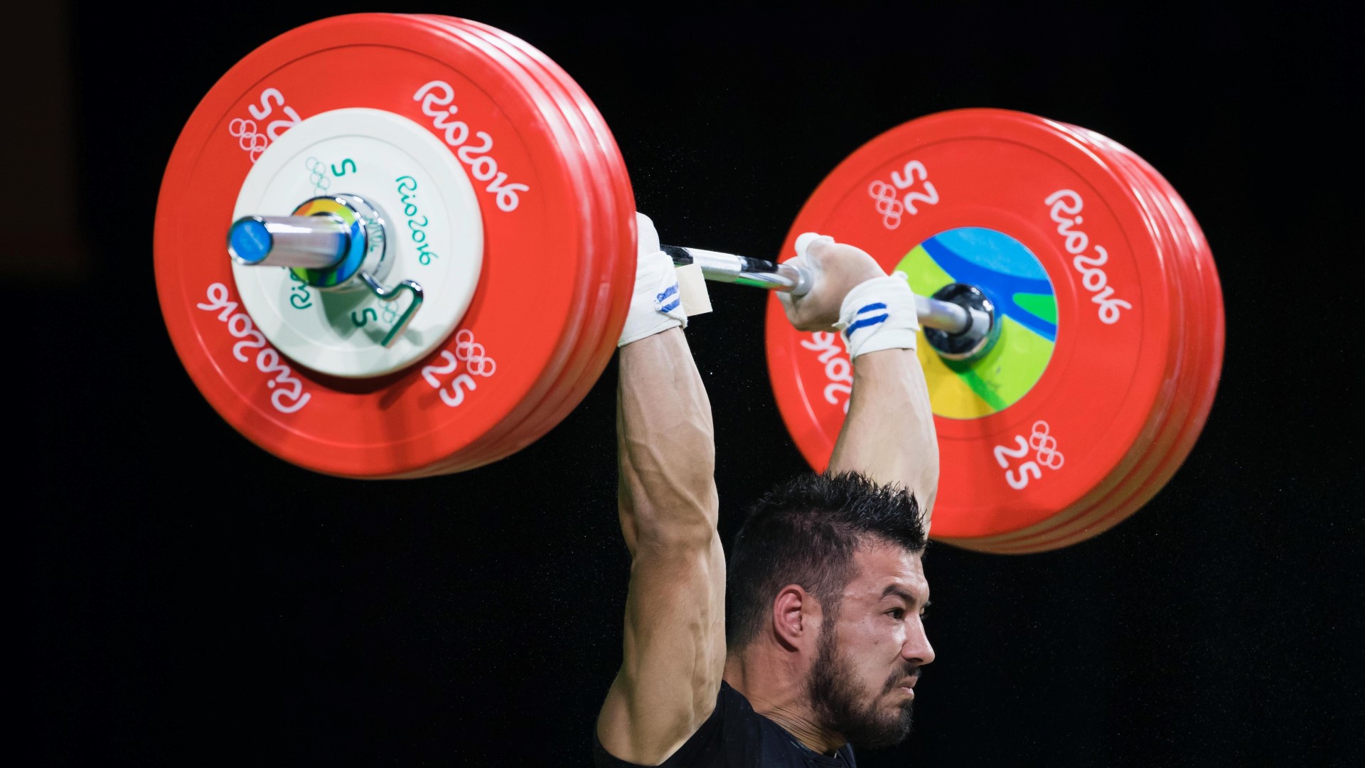 Man lifting weights over his head during an Olympic competition.