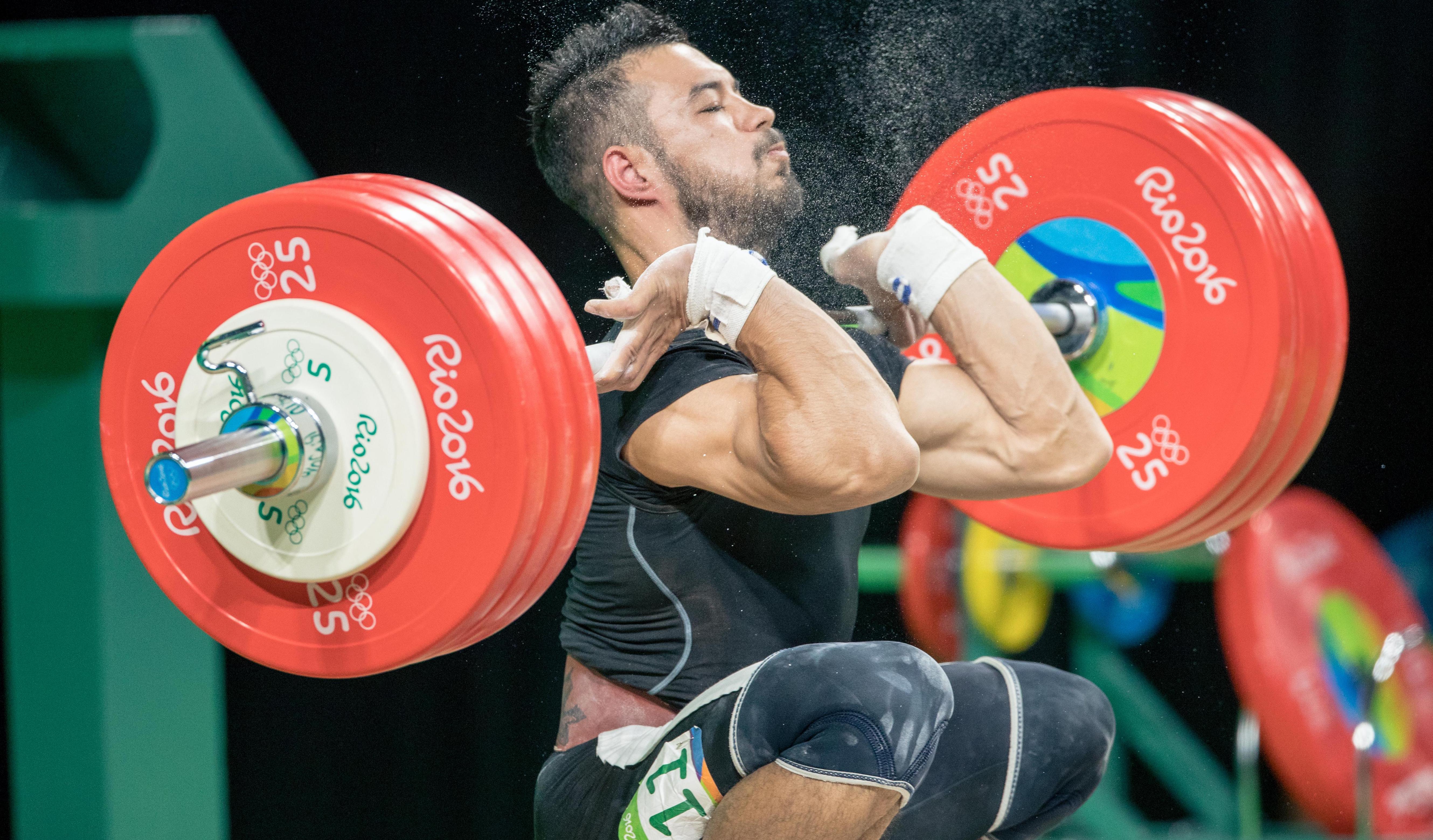 Athlete lifting weights, having the weights on his chest, getting ready to lift.